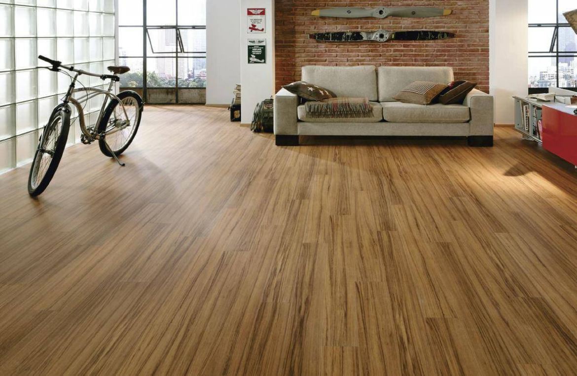 Piso laminado em ambiente com sofá e bicicleta